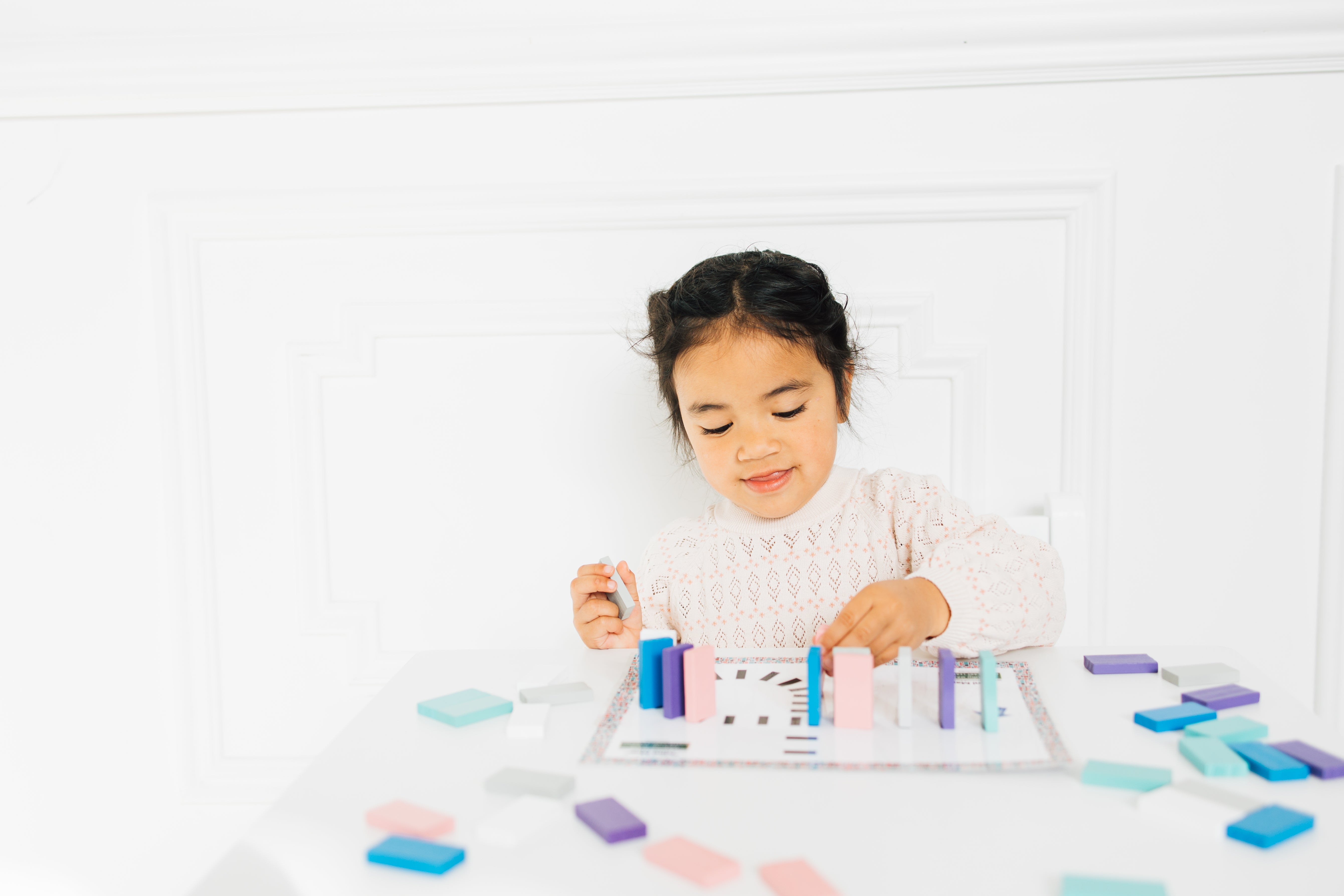 Little girl playing with Montessori inspired mini domino map toy. 